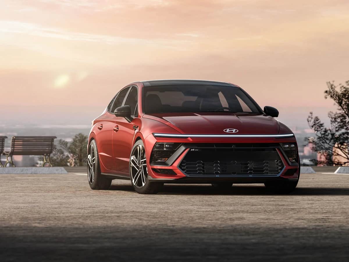 Red 2026 Hyundai Sonata N Line parked at a lookout at sunset, with benches and a city in the distance