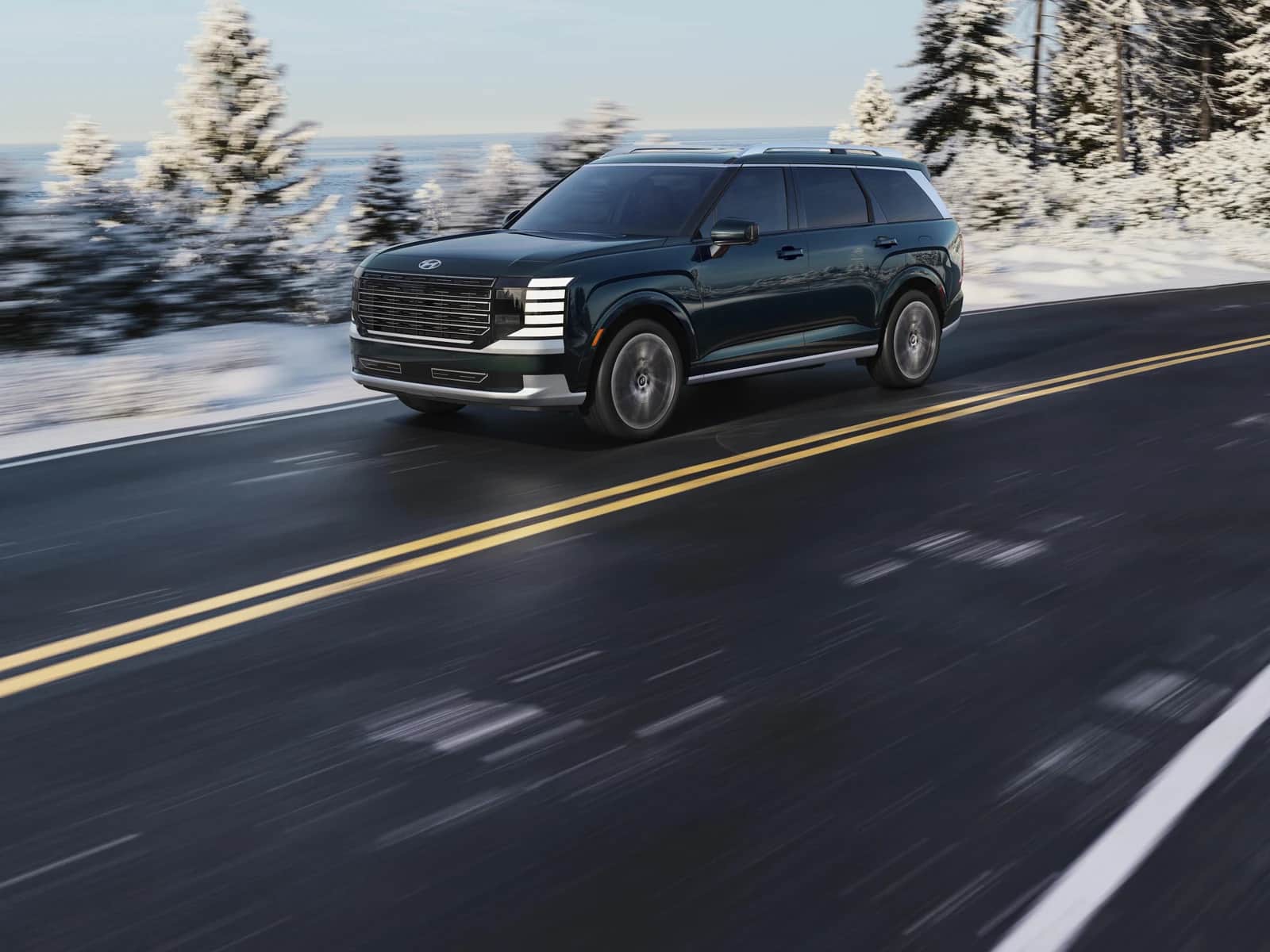 Hyundai Palisade 2026 vert foncé sur une route d'hiver déneigée, conifères enneigés de chaque côté