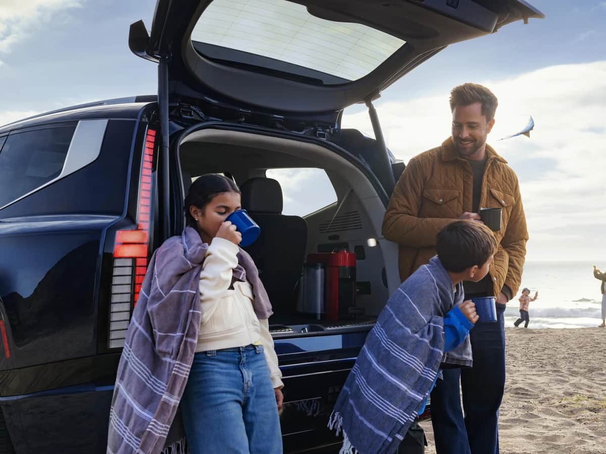 Famille qui prend une pause au hayon ouvert d'un Hyundai IONIQ 9 2026, sur une plage