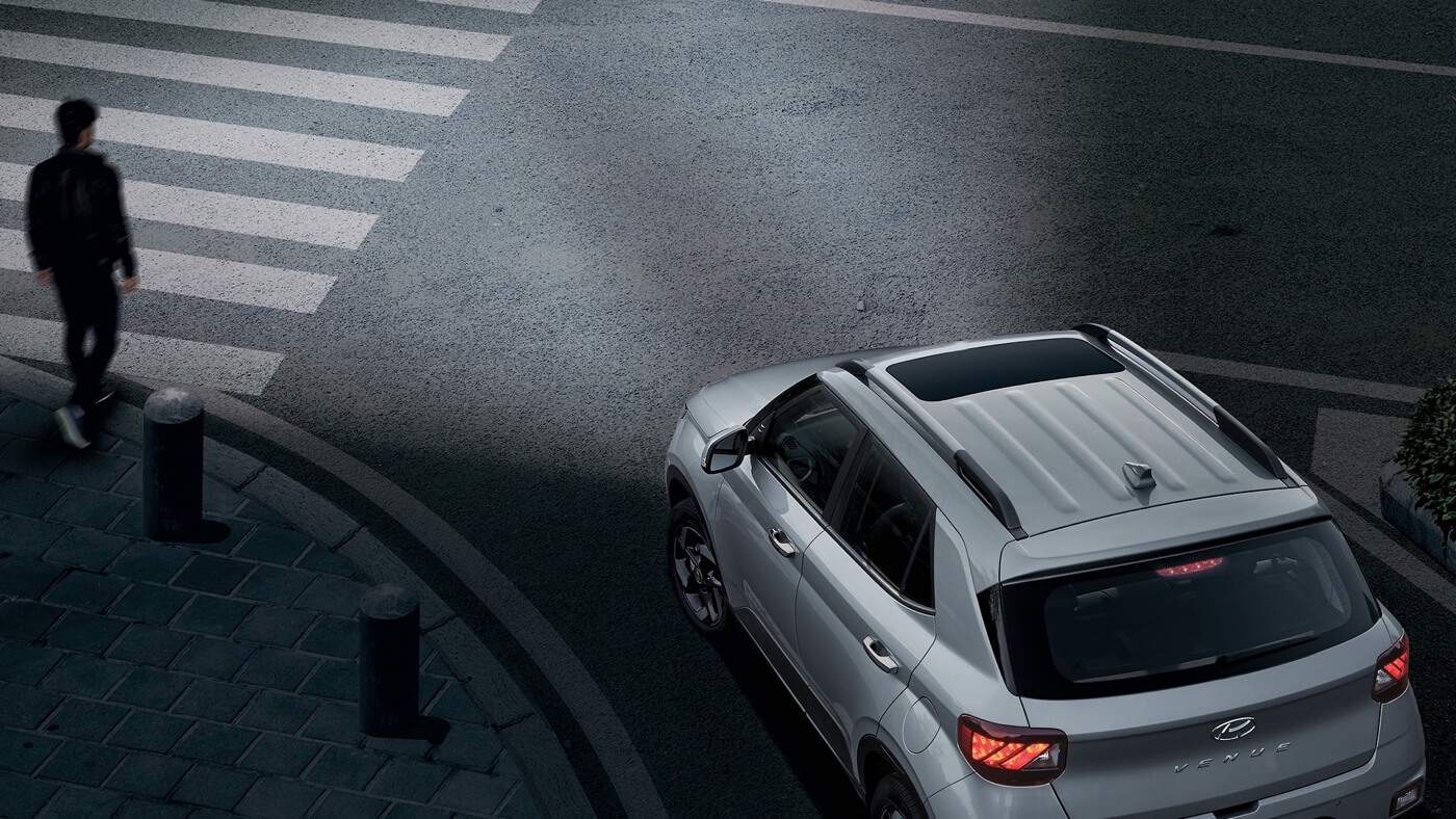 Le Hyundai Venue 2025 alerte en tout temps en laissant passer un piéton dans une rue.