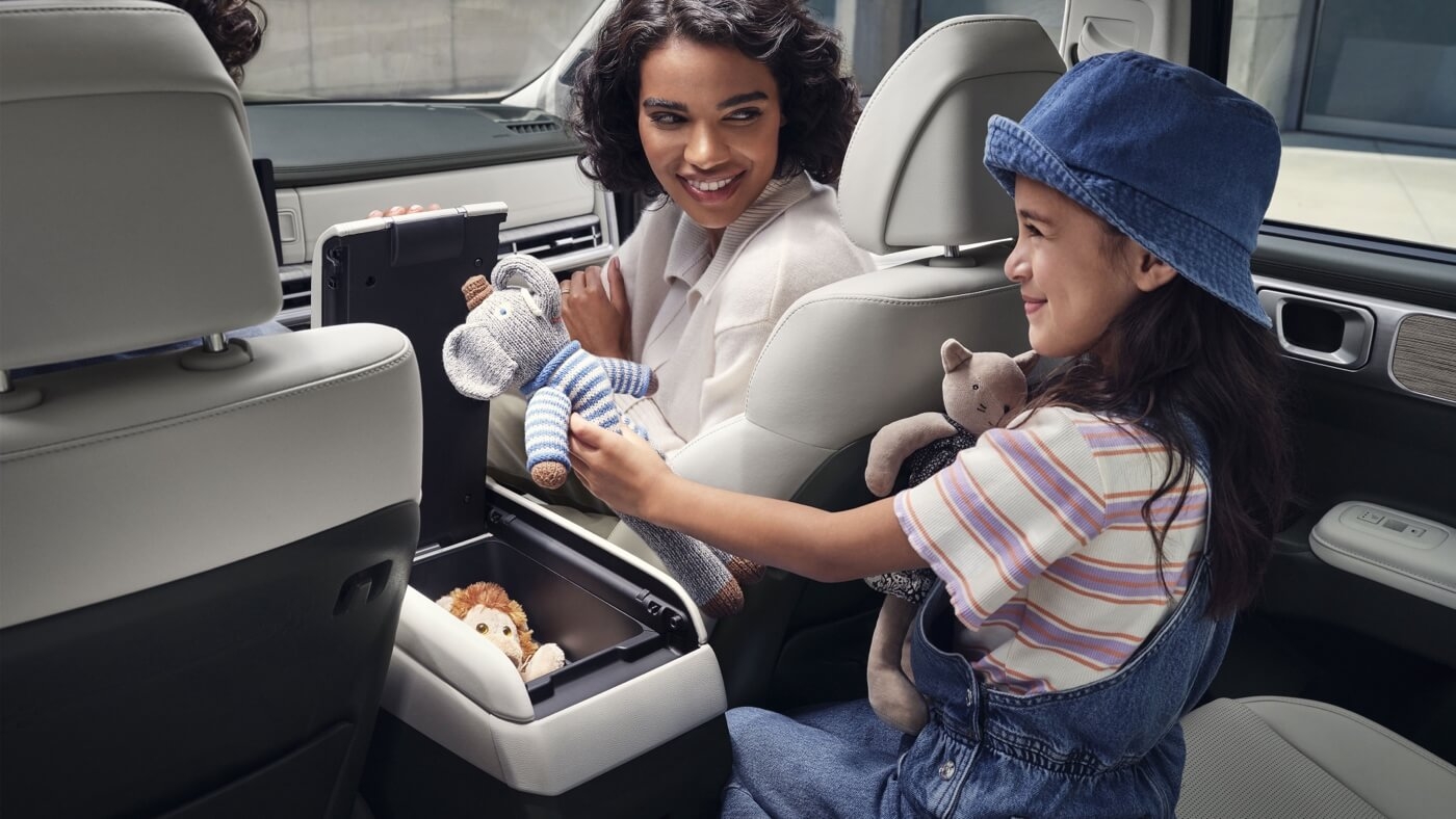 Mère et sa fille insérant des poupées dans la console centrale du Hyundai Santa Fe 2025.