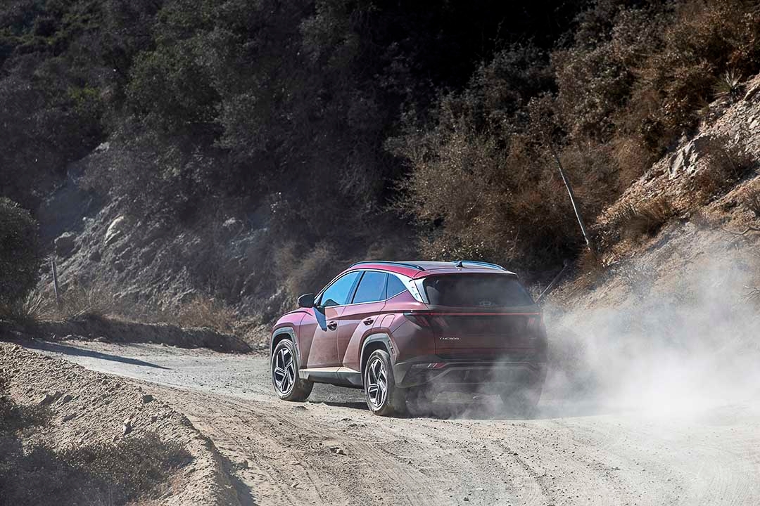 vue trois quart arrière du Hyundai Tucson 2022 roulant sur un sentier de terre