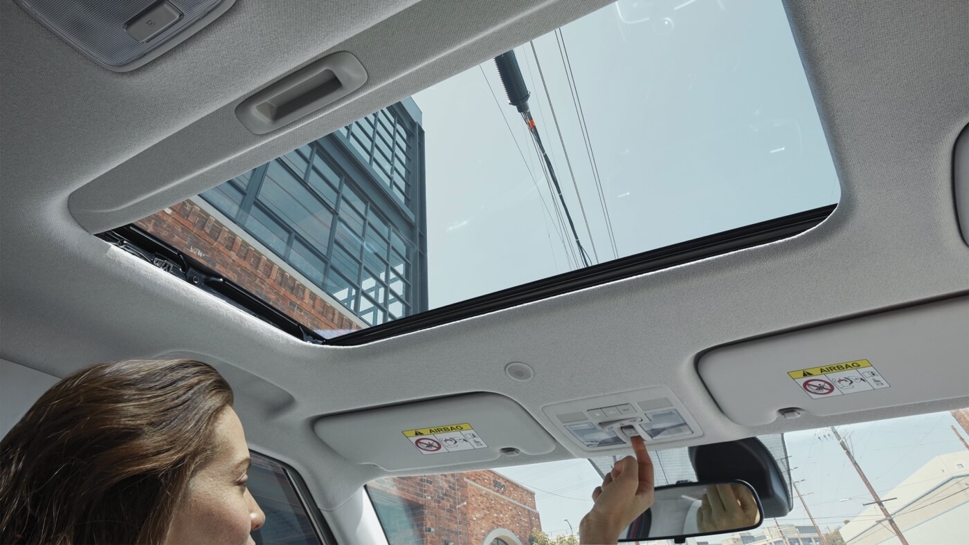 Femme au volant du Hyundai Venue 2025 ajustant le toit ouvrant électrique.